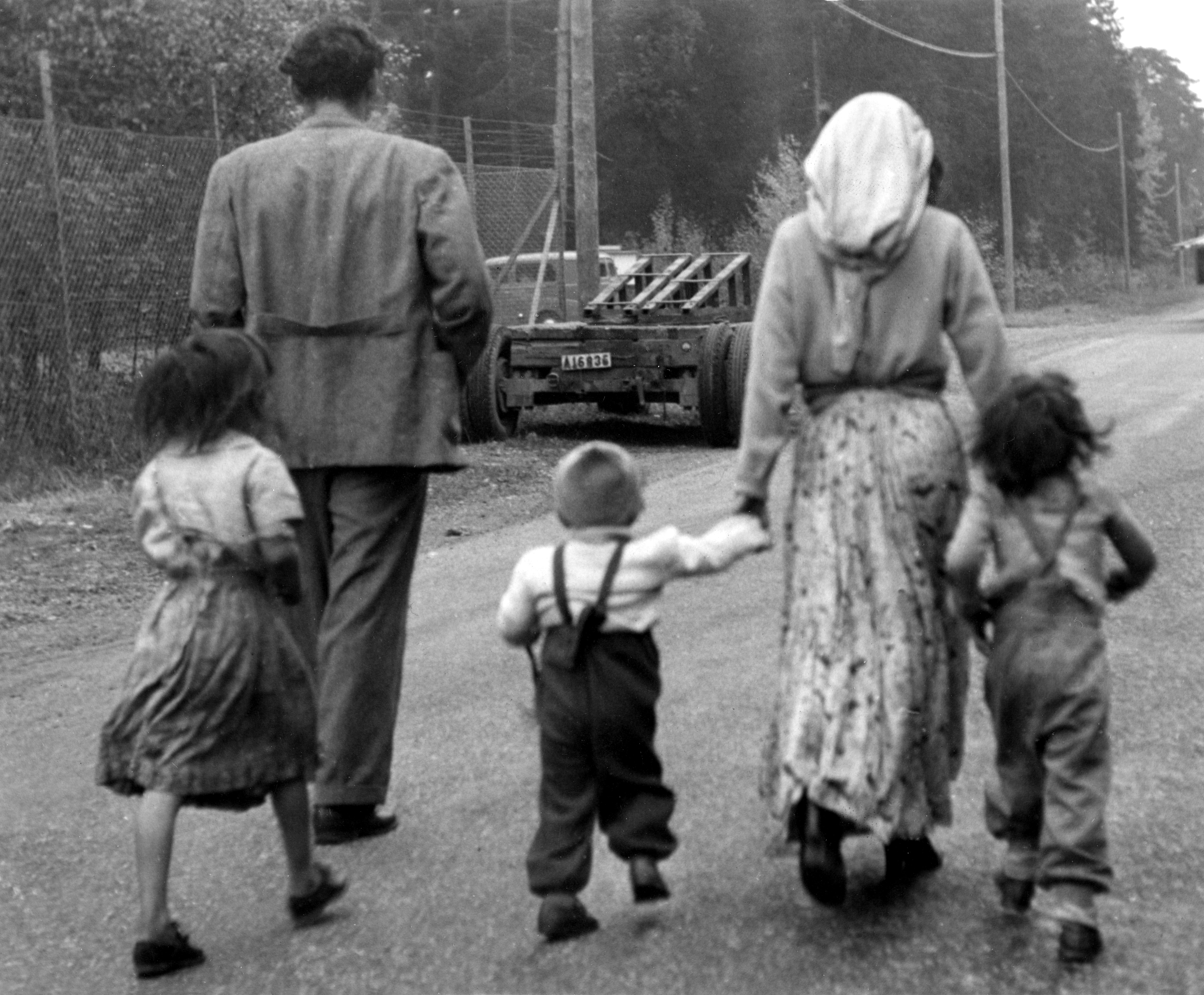 En romsk familj med tre barn vandrar bort på vägen efter att ha vräkts från sitt tältläger på Mälarhöjdens Idrottsplats 12:e oktober 1951.