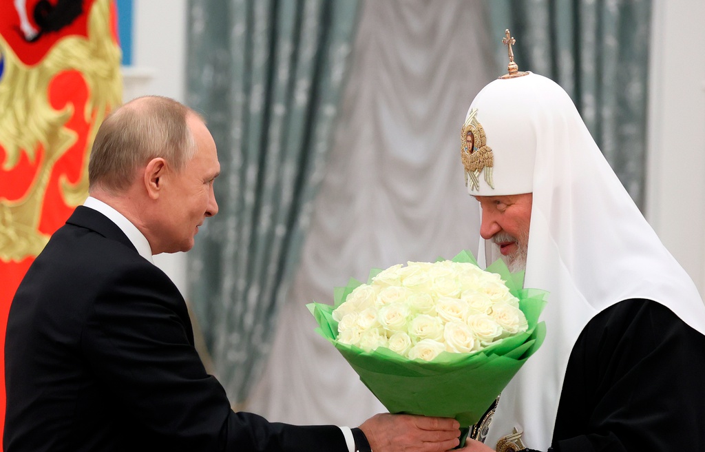 Vladimir Putin förärar den rysk-ortodoxe patriarken med en bukett. Kirill vill att ryssar visar en helt enad front bakom Putins krigslinje. Arkivbild.