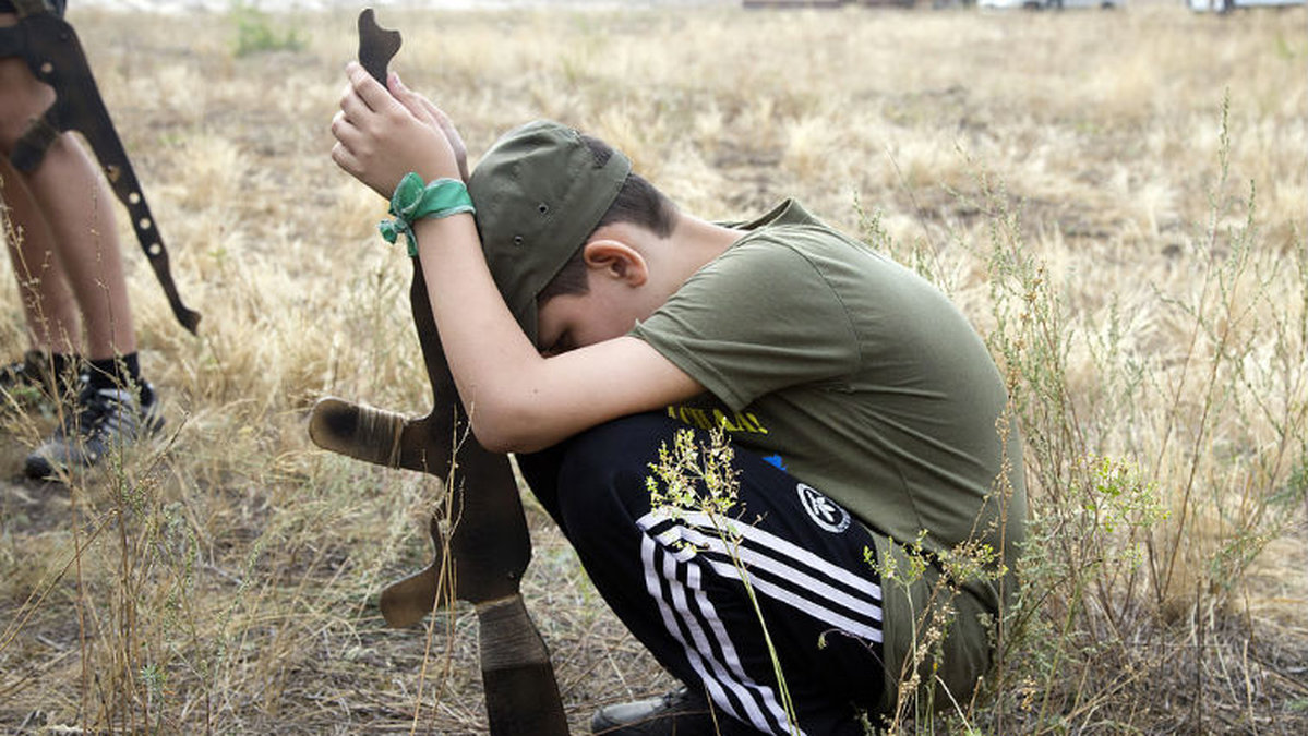 En ung pojke tar en paus i augusti 2015. Pojken medverkade under en militärträning i en by utanför Kiev där yrkesutbildade militärer lär barn att hantera vapen.