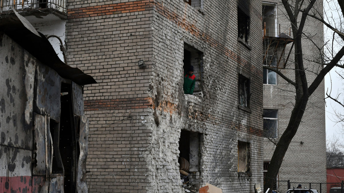 En invånare tittar ut genom en fönsterglugg i ett bostadshus efter en rysk raketattack i Zaporizjzja. Arkivbild.