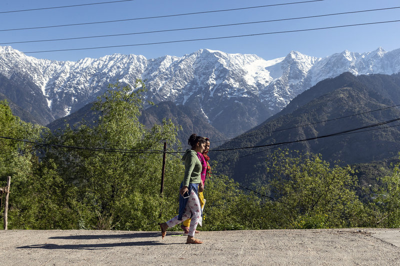 Promenerande kvinnor framför de snö- och istäckta Dhauladhar-bergen i Himalaya.