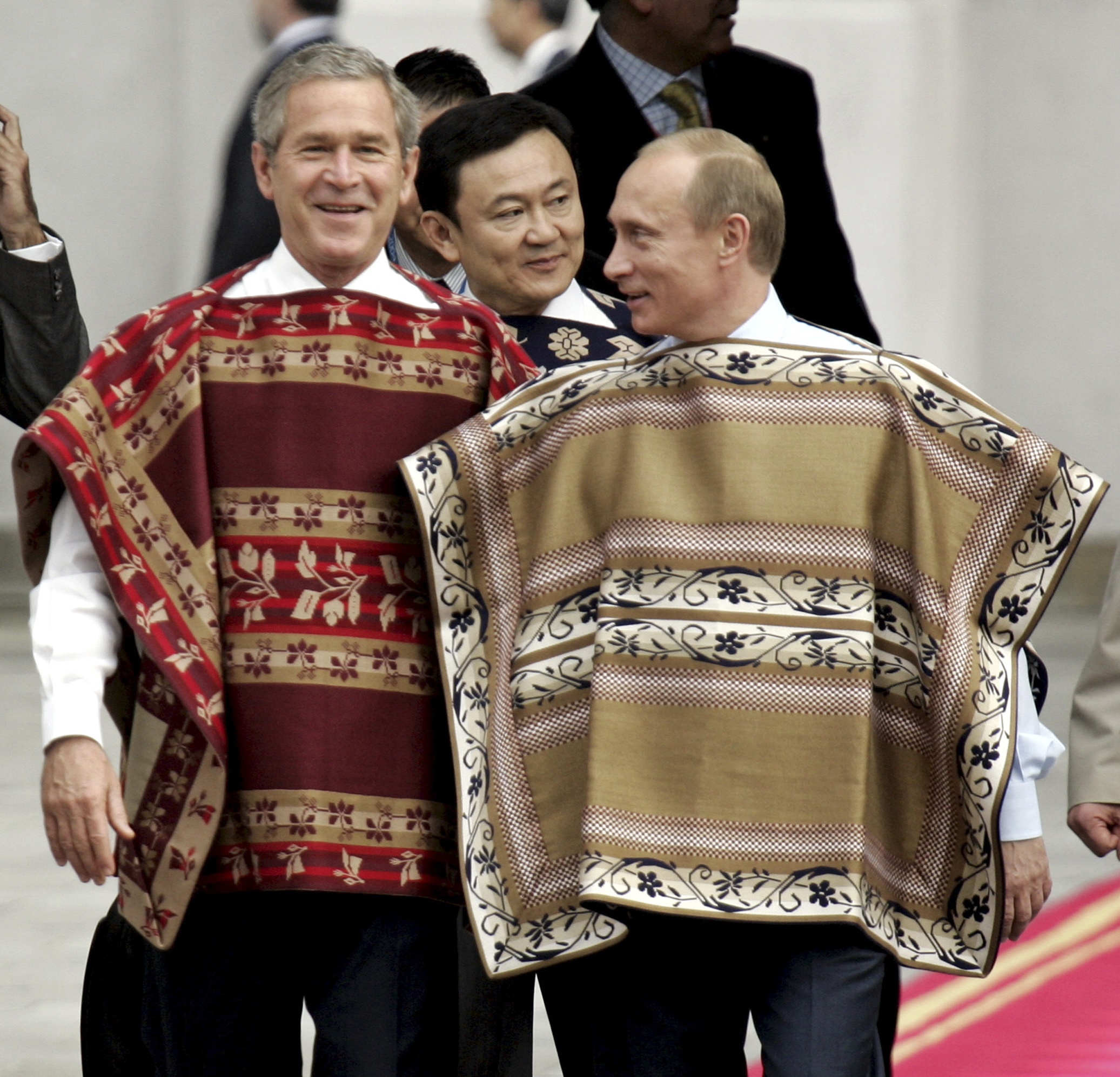 Vem sa att ponchos inte är macho? Här ses ryssen med ex-presidenten George W Bush, till vänster.