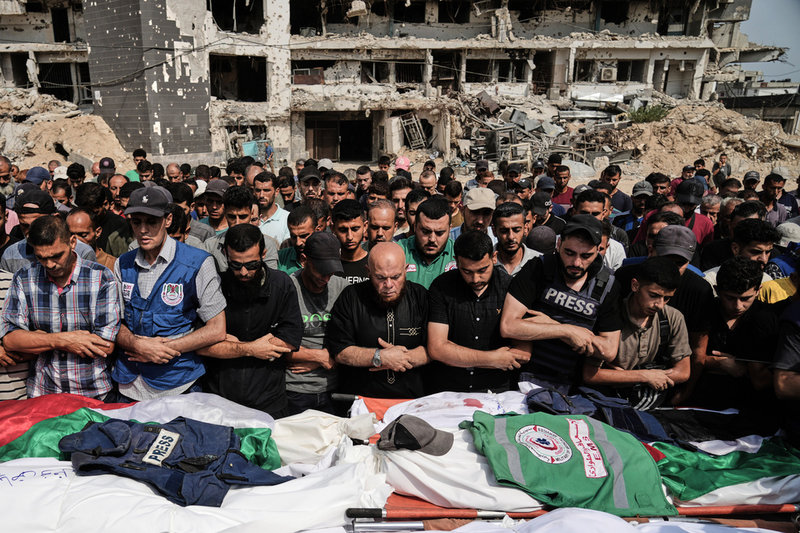 Palestinier har samlats för att sörja de dödade journalisterna under deras begravning på måndagen.