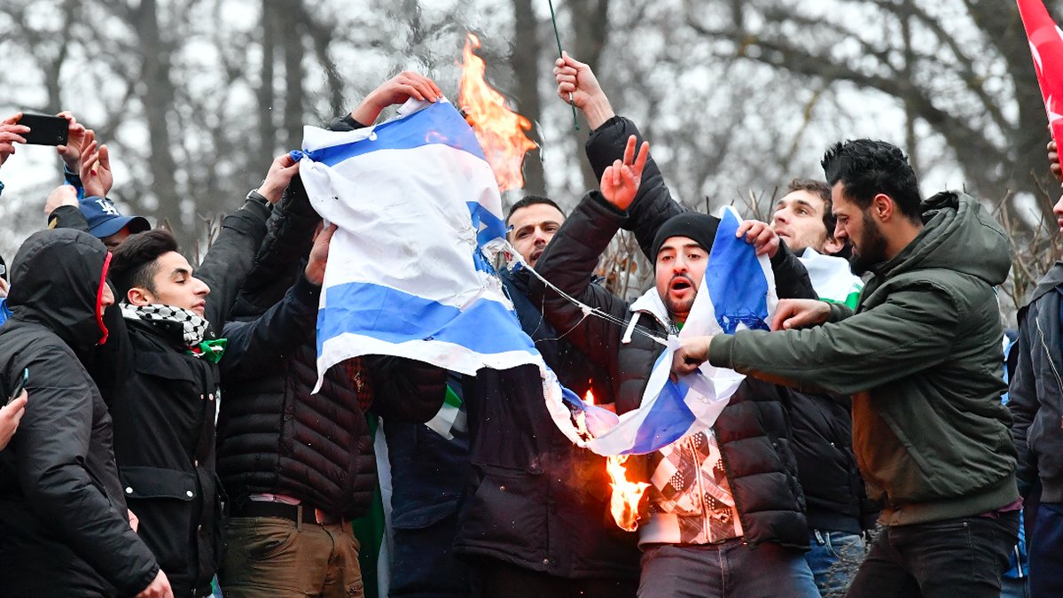 Demonstranter bränner en israelisk flagga.
