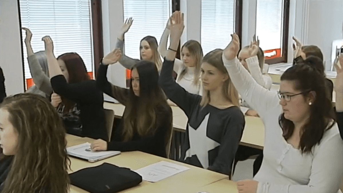 Alla tjejer i klassrummet räcker upp handen. 