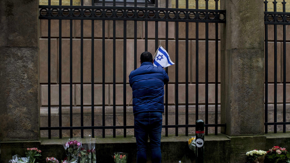 En man sätter en israelisk flagga utanför synagogan. 