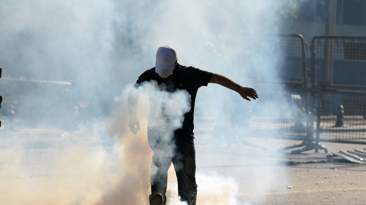 En demonstrant försöker komma undan tårgasen.