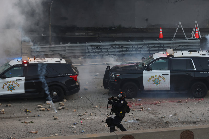 En polis möts av stenkastning i centrala Los Angeles på söndagen.