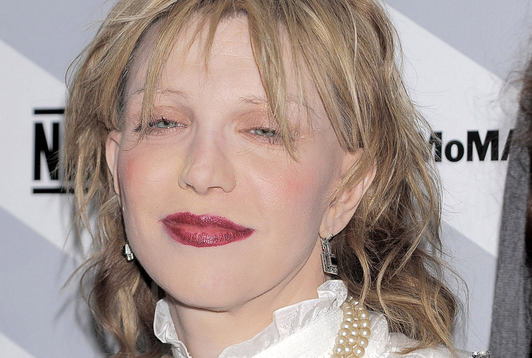 Courtney Love med blödande läppstift, genomskinlig hud, bortplockade ögonbryn och två rosa bollar på kinderna. Varför? Courtney Love med blödande läppstift, genomskinlig hud, bortplockade ögonbryn och två rosa bollar på kinderna. Varför?