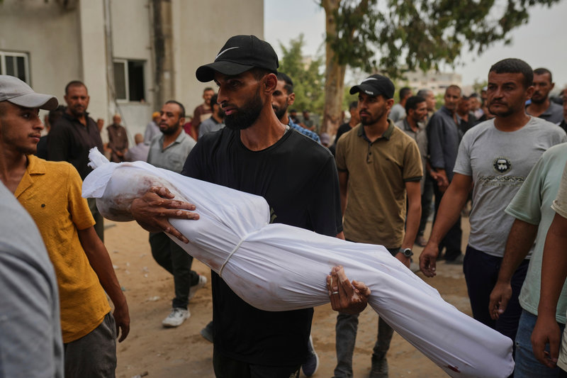 En pojke som dödats av israelisk beskjutning bärs av en släkting under begravningen utanför Shifasjukhuset i Gaza city på torsdagen.