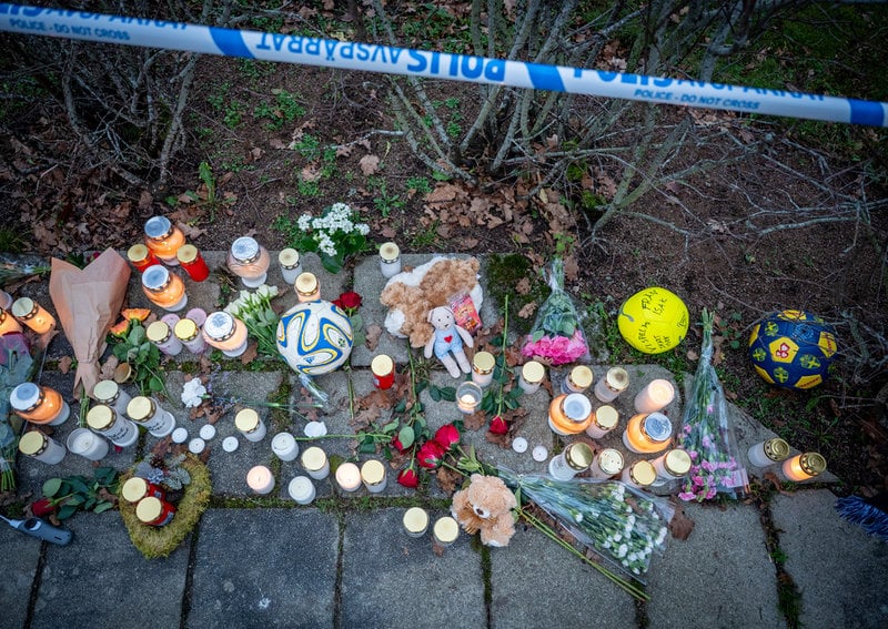 Blommor, ljus och föremål på minnesplatsen utanför avspärrningen i bostadsområdet i Hörby på torsdagen.