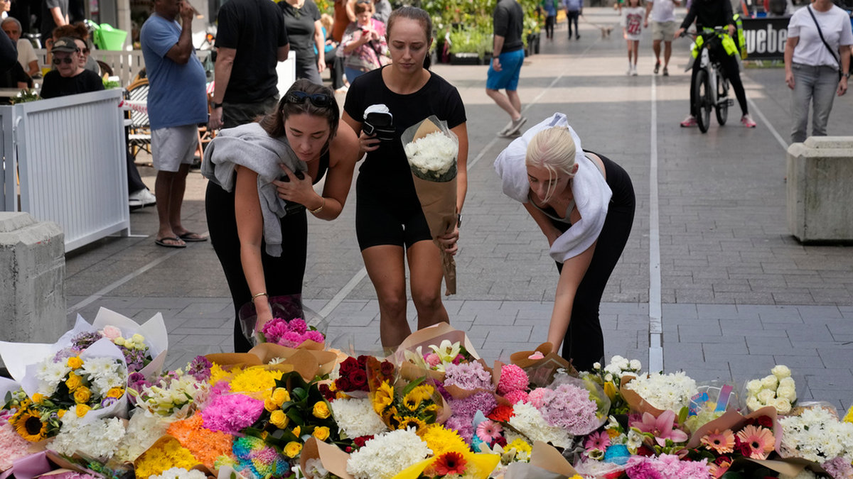 Tre kvinnor lägger blommor nära köpcentrumet i östra Sydney söndagen den 14 april, efter att flera personer knivhuggits till döds dagen innan.