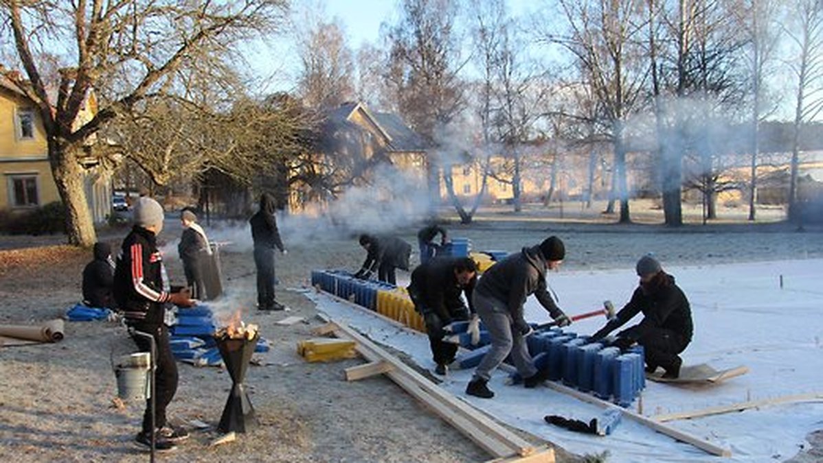 Med 3 400 träbitar ska flyktingarna bygga en stor Sverigeflagga för att hylla svenskarna. 