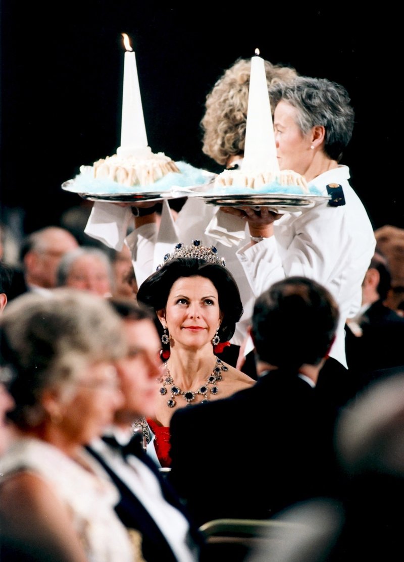 Servitriser bär på desserten över huvudet på Sveriges drottning Silvia under Nobelbanketten i Stockholms stadshus 10 december 1991. Arkivbild.